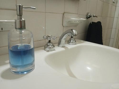 a glass bottle of water sitting on a bathroom sink at Habitación privada zona Centro, Tribunales y Patio Olmos in Cordoba