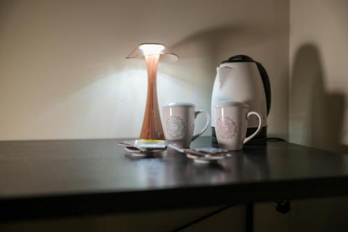a table with two coffee cups and a lamp on it at Palazzo Giudecca in Reggio Calabria