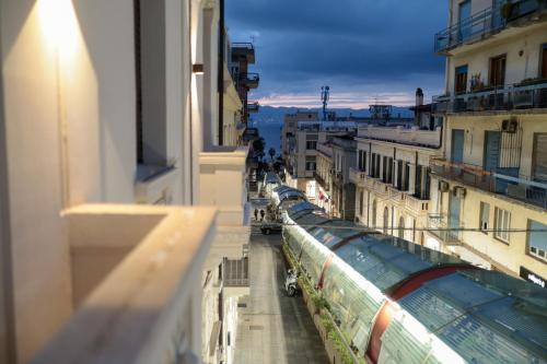 a train traveling down a city street with buildings at Palazzo Giudecca in Reggio Calabria