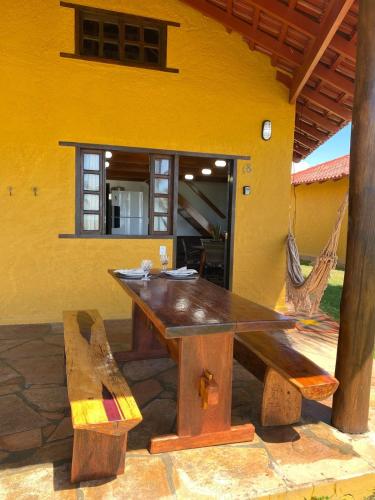 a wooden table and bench in front of a yellow building at Bangalô Mar & Sol in Alcobaça