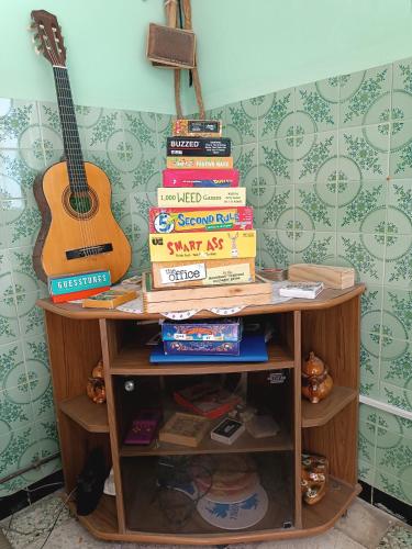 a stack of books on a shelf with a guitar at Dar Hkaïem in Hammam Sousse