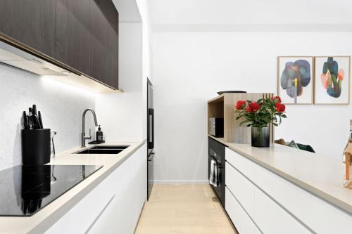 a kitchen with white counters and black cabinets at Mod House Ocean Grove- Walk to the shops, cafes, beach and park! Brand new luxury apartment in gated complex in Ocean Grove