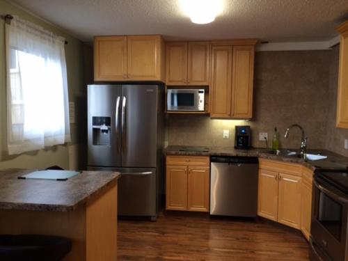 una cocina con electrodomésticos de acero inoxidable y armarios de madera en Laura's Lodge en Saskatoon
