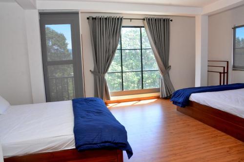 a bedroom with two beds and a large window at High Cliff Villa in Nuwara Eliya