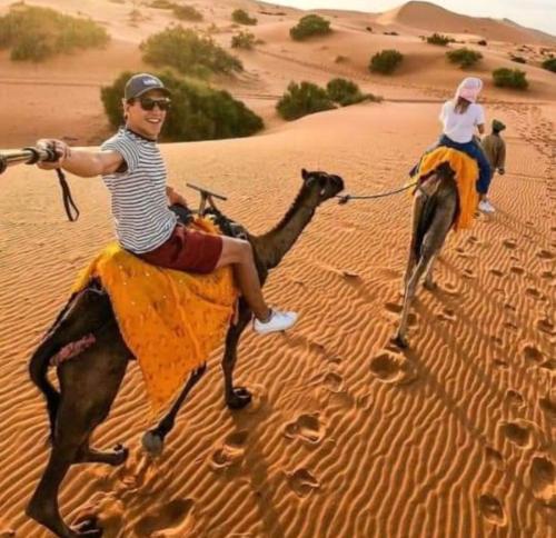 two people riding on camels in the desert at Private Luxury Camp in Merzouga