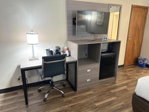 a room with a desk with a television and a chair at Clarion Inn in Fort Collins