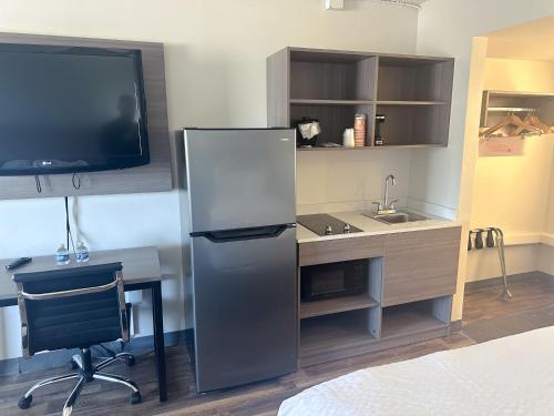 a kitchen with a refrigerator and a desk with a tv at Clarion Inn in Fort Collins