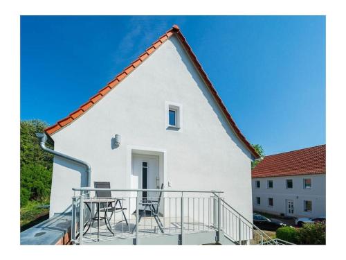 a white building with a table and chairs on a balcony at Holiday Apartment Haus Turmblick in Großzschepa