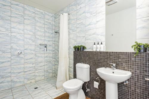 a bathroom with a toilet and a sink and a shower at Perfect Family Getaway in Point Lonsdale