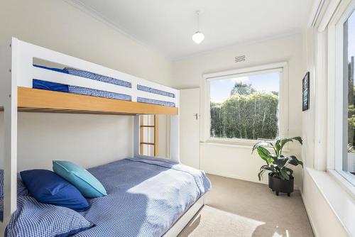 a bedroom with a bed with blue pillows and a window at Perfect Family Getaway in Point Lonsdale
