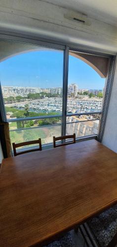 - une table dans une chambre avec une grande fenêtre dans l'établissement Carnon plage Agréable F2 loggia vue port parking, à Carnon-Plage