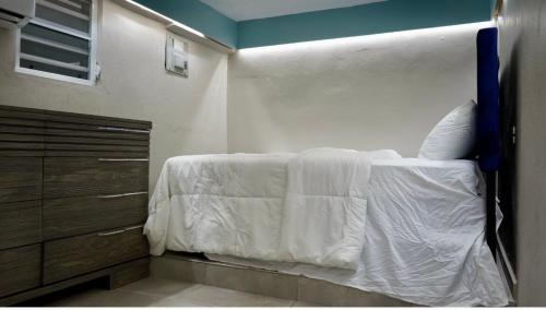 a bedroom with a bed with white sheets and a dresser at Casa Cayito Agua Dulce in Arecibo