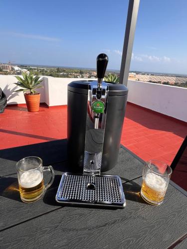 a coffee maker on a table with two glasses of beer at Green Apartment in Tavira Garden in Tavira