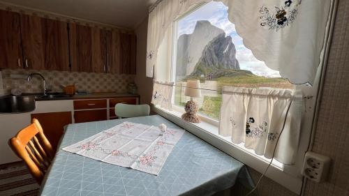 a kitchen with a table and a window with a mountain view at Prestholmen Værøy Lofoten in Værøy