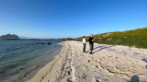 a man and a woman walking on the beach at Prestholmen Værøy Lofoten in Værøy