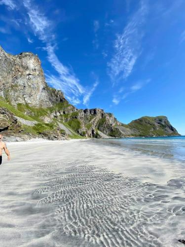 a man walking on a beach with mountains in the background at Prestholmen Værøy Lofoten in Værøy
