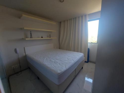 a white bed in a room with a window at Flat 2 quartos Resort Marulhos Porto de Galinhas C401 in Porto De Galinhas