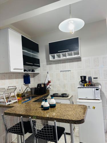 a kitchen with a counter and a white refrigerator at Apto aconchegante perto da praia in Vila Velha