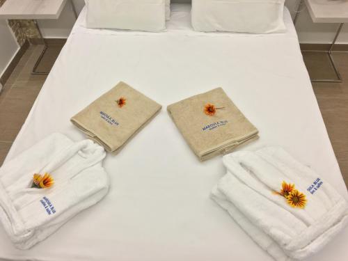 a white bed with two towels and a pair ofippers at Casa Blue Sarantis in Faliraki