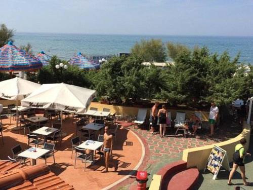 a patio with tables and white umbrellas and the ocean at Centro Turistico San Nicola in Peschici