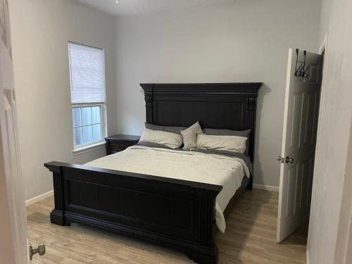 Cama negra en habitación con ventana en Simple Modern House, en Oklahoma City