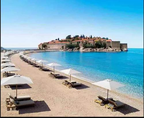 a beach with chairs and umbrellas and the ocean at Horizon Two bedroom Penthouse with Hot tub in Becici