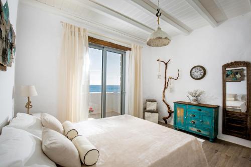 a white bedroom with a large bed and a window at Axiotheaton Villas in Pefki Rhodes