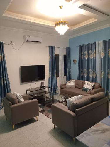 a living room with two couches and a flat screen tv at Appartements PALOU in Motsouémbé