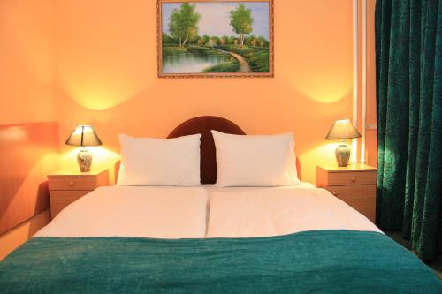 een slaapkamer met een groot bed met 2 lampen bij Hotel Ózd in Ózd