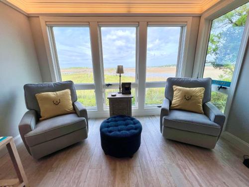 Dos sillas y una otomana en una habitación con ventanas. en 2112 Landfall Way, en Seabrook Island