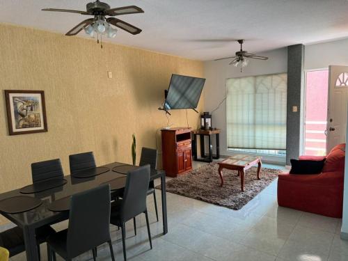 a living room with a table and a red couch at Departamento céntrico en Boca del Rio con alberca in Boca del Río