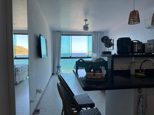 a kitchen with two chairs and a counter with a view of the ocean at Arraial do cabo loft prainha in Arraial do Cabo