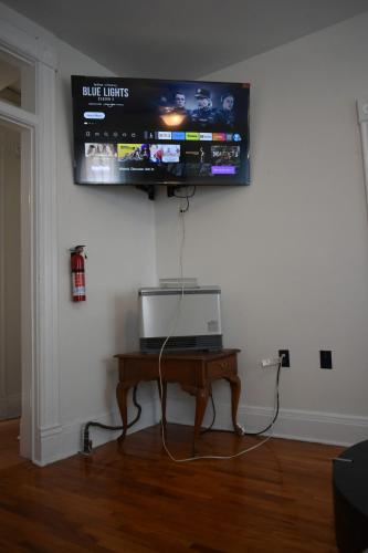 a television on a wall with a table with a laptop at Downtown Lima 1 Bdrm Haven! in Lima