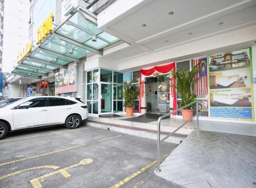 a white car parked in front of a building at Grand Inn Hotel - Macalister Road in George Town