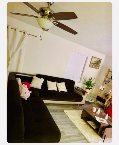 a living room with a black couch and a ceiling fan at Warmth Private Room in Stillwater Lake Estates