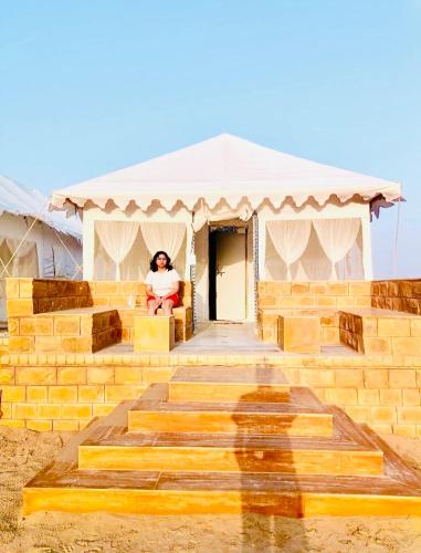 a woman sitting on the steps of a tent at Jaisalmer Sand Dunes Luxury Camp And Resort in Jaisalmer