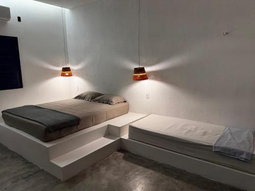 a bedroom with two beds and two lights on the wall at Casa Woody in Santo Amaro