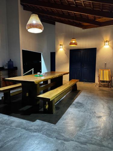 a wooden table and bench in a room with lights at Casa Woody in Santo Amaro
