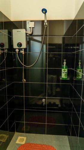 a shower with a hose attached to a tiled wall at Serene Homes 03 in Kampala