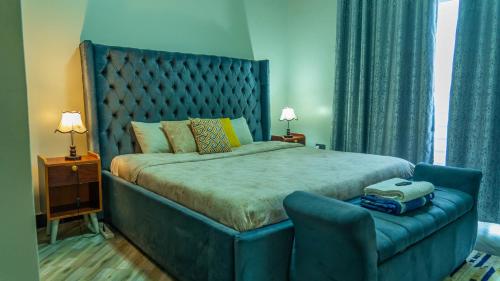 a bedroom with a large bed with a blue headboard at Serene Homes 03 in Kampala