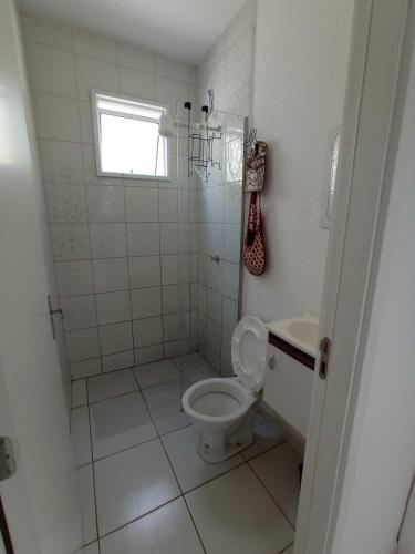 a white bathroom with a toilet and a sink at Casa de férias Pôr do Sol in Presidente Epitácio