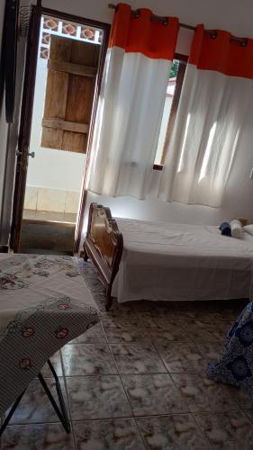 a bedroom with a bed with curtains and a chair at Hospedagem, Pouso Famíliar Paraty in Paraty
