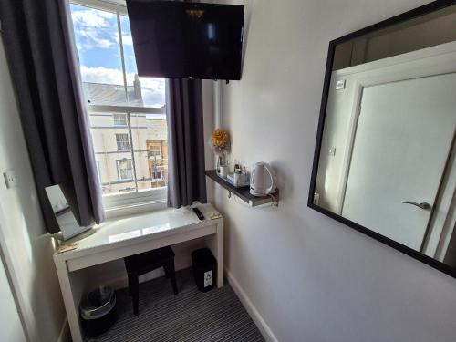 a bathroom with a sink and a mirror and a window at Miricia Guest House in Scarborough