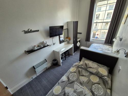 a small room with a bedroom with a bed and a desk at Miricia Guest House in Scarborough