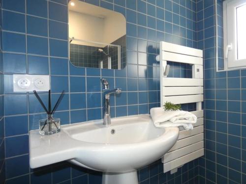 La salle de bains est pourvue de carrelage bleu, d'un lavabo et d'un miroir. dans l'établissement Maison rénovée à Notre Dame de Monts, 4 pers, proche plage - FR-1-540-317, à Notre-Dame-de-Monts