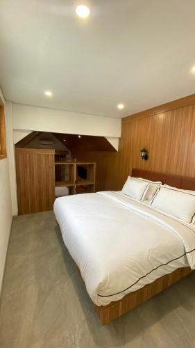 a large white bed in a bedroom with wooden walls at Playa La Barka Resort by Raminten in Moyudan