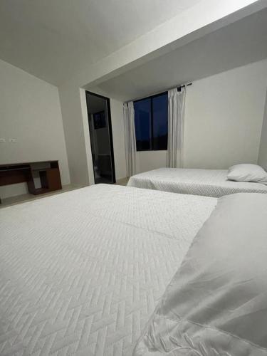two white beds in a room with a window at CASARENA Casa campestre con apartamentos independientes en los llanos in Villavicencio
