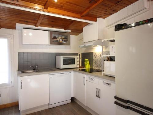 La cuisine est équipée de placards blancs et d'un four micro-ondes blanc. dans l'établissement Appartement spacieux au Mont-Dore : 10 couchages, WIFI, proche thermes, animaux acceptés - FR-1-415-72, à Le Mont-Dore