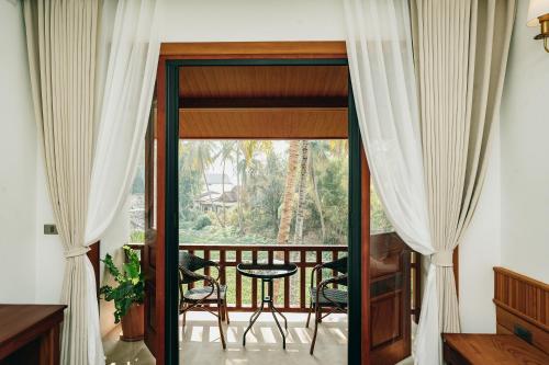 a room with a balcony with a view of the jungle at Asoca Hotel Luang Prabang in Luang Prabang