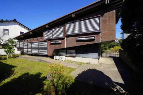 a building with shutters on the side of it at 建築家渡邊洋治設計 斜めの家 The Diagonal House in Joetsu